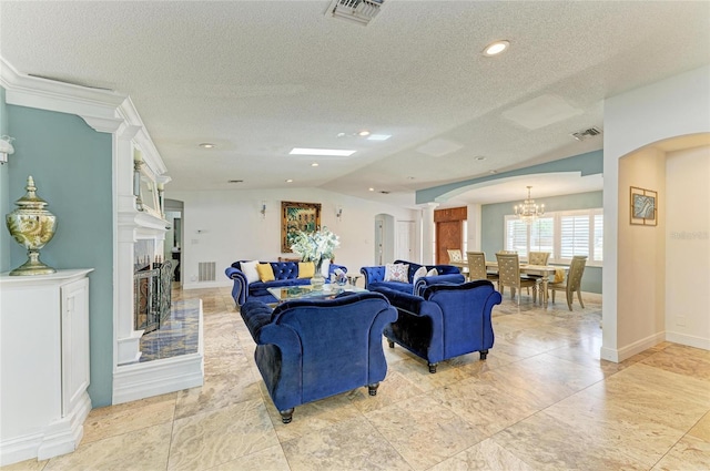 2726 Desoto Rd, Sarasota, FL 34234 - living area with arched walkways, a chandelier, a textured ceiling, ornate columns, and a fireplace