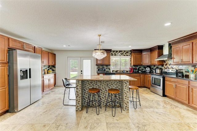 2726 Desoto Rd, Sarasota, FL 34234 - kitchen featuring appliances with stainless steel finishes, wall chimney range hood, backsplash, a center island, and a breakfast bar