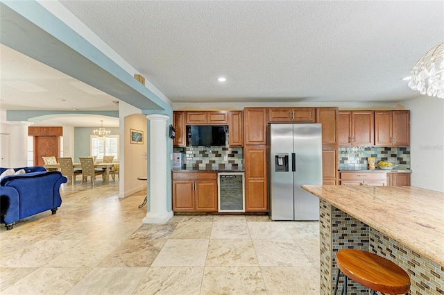 2726 Desoto Rd, Sarasota, FL 34234 - kitchen with stainless steel refrigerator with ice dispenser, decorative columns, beverage cooler, a chandelier, and decorative backsplash