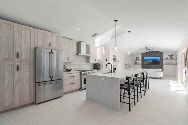 1527 Buoy Ln, Osprey, FL 34229 - kitchen featuring high end appliances, wall chimney exhaust hood, lofted ceiling, light brown cabinetry, and open floor plan