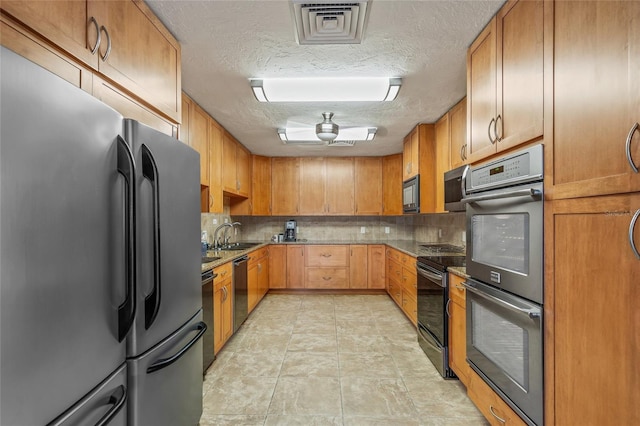 1527 Buoy Ln, Osprey, FL 34229 - kitchen featuring black appliances, a textured ceiling, backsplash, stone countertops, and brown cabinets