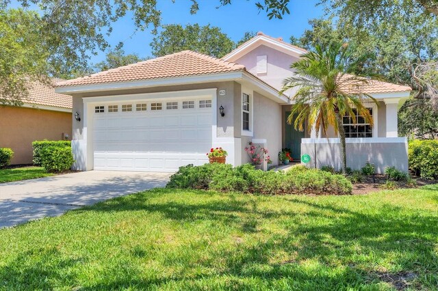 4121 Reflections Pkwy, Sarasota, FL 34233 - mediterranean / spanish house featuring a tiled roof, stucco siding, a garage, a front lawn, and driveway