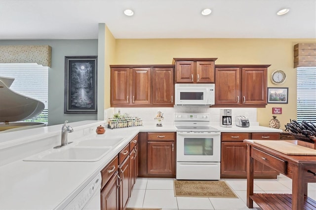 4121 Reflections Pkwy, Sarasota, FL 34233 - kitchen with white appliances, a sink, light countertops, tasteful backsplash, and light tile patterned flooring