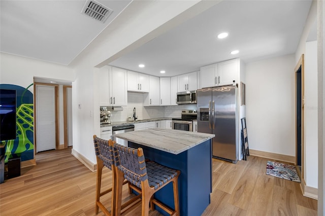 440 42nd St N, Saint Petersburg, FL 33713 - kitchen with stainless steel appliances, light stone counters, white cabinets, a sink, and recessed lighting