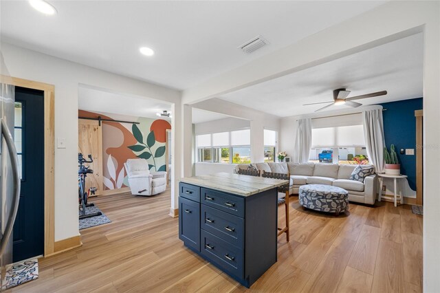 440 42nd St N, Saint Petersburg, FL 33713 - kitchen with open floor plan, light wood-style floors, a kitchen bar, blue cabinets, and a ceiling fan