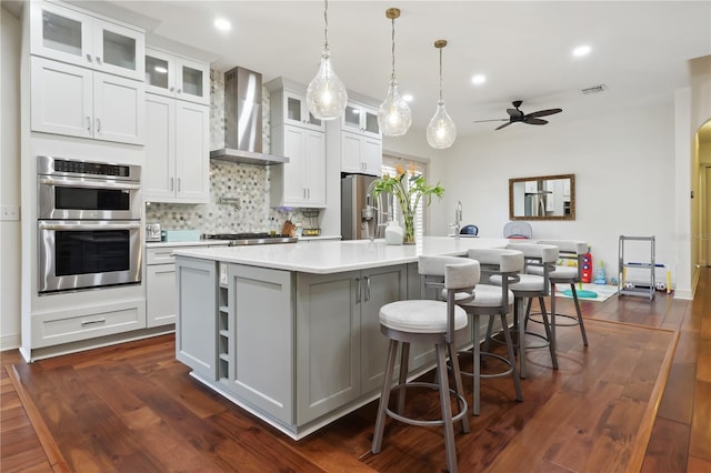 4696 Del Sol Blvd, Sarasota, FL 34243 - kitchen featuring wall chimney range hood, a spacious island, ceiling fan, stainless steel appliances, and light countertops