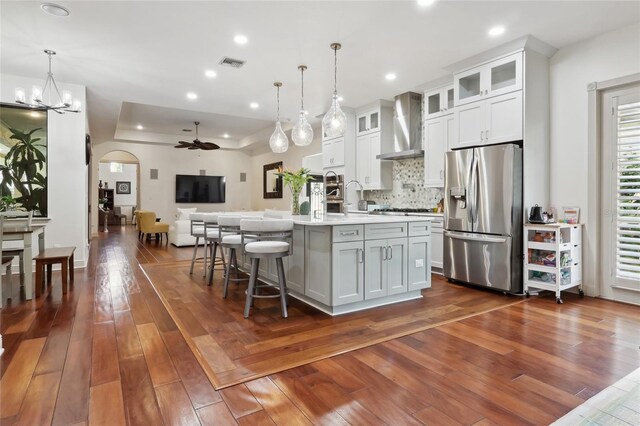 4696 Del Sol Blvd, Sarasota, FL 34243 - kitchen featuring stainless steel appliances, wall chimney range hood, light countertops, arched walkways, and open floor plan