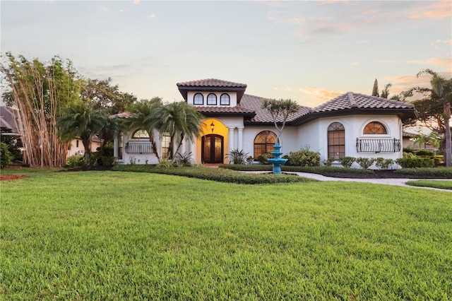 4696 Del Sol Blvd, Sarasota, FL 34243 - mediterranean / spanish house with french doors, a front lawn, stucco siding, and a tiled roof