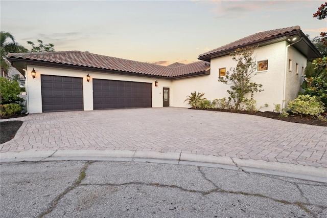 4696 Del Sol Blvd, Sarasota, FL 34243 - mediterranean / spanish-style house featuring an attached garage, decorative driveway, stucco siding, and a tiled roof