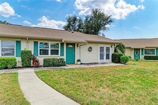 1906 Canterbury Ln Unit 16, Sun City Center, FL 33573 - view of front of home with stucco siding, a front lawn, and french doors