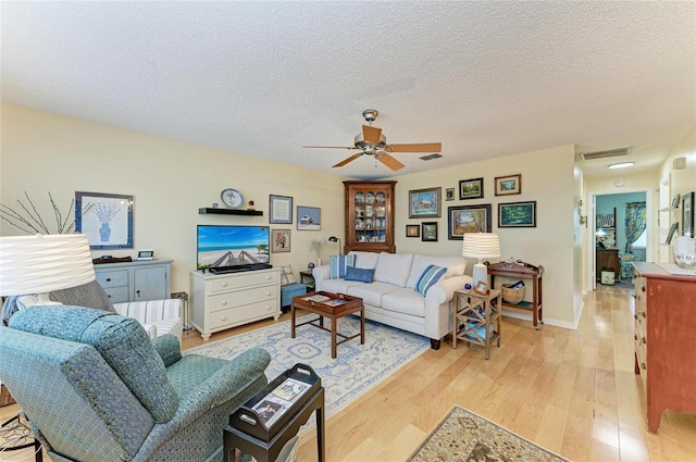 1906 Canterbury Ln Unit 16, Sun City Center, FL 33573 - living area with light wood-type flooring, a ceiling fan, a textured ceiling, and baseboards