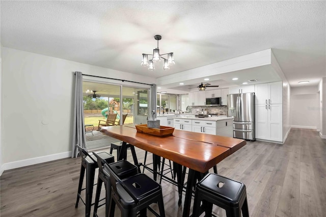 2255 61st St, Sarasota, FL 34243 - dining area with baseboards, light wood-style flooring, a textured ceiling, a chandelier, and a ceiling fan