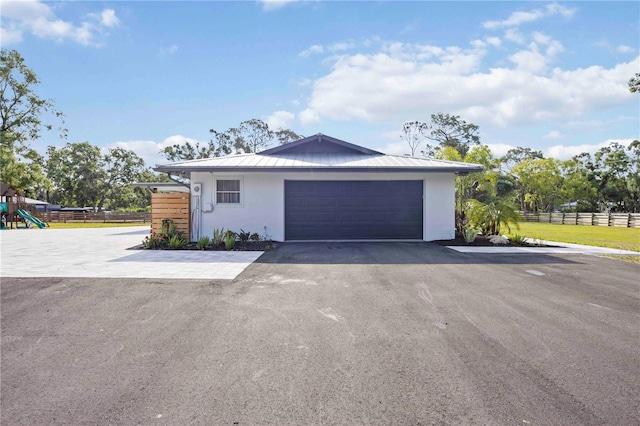 2255 61st St, Sarasota, FL 34243 - view of property exterior featuring stucco siding, metal roof, a standing seam roof, a garage, and asphalt driveway