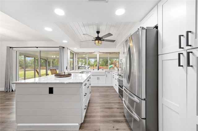 2255 61st St, Sarasota, FL 34243 - kitchen featuring stainless steel appliances, light stone countertops, white cabinetry, recessed lighting, and a kitchen island