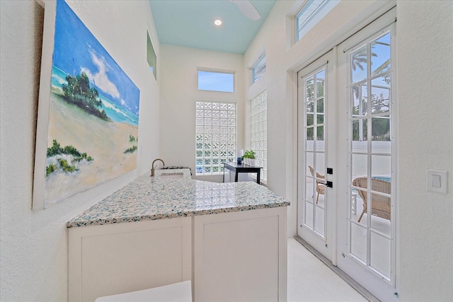 7507 Ascot Ct, University Park, FL 34201 - kitchen with french doors, light stone counters, a textured wall, white cabinetry, and recessed lighting