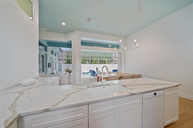 7507 Ascot Ct, University Park, FL 34201 - kitchen featuring white dishwasher, white cabinets, light stone counters, and light wood-style floors