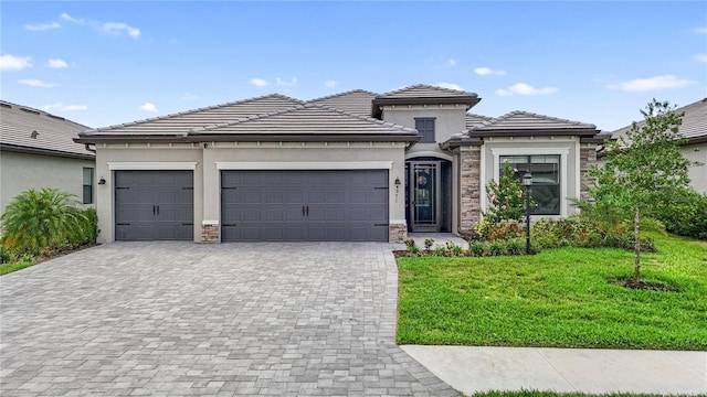 4971 Oyster Pearl St, Bradenton, FL 34211 - prairie-style house featuring decorative driveway, a garage, a front yard, stone siding, and stucco siding