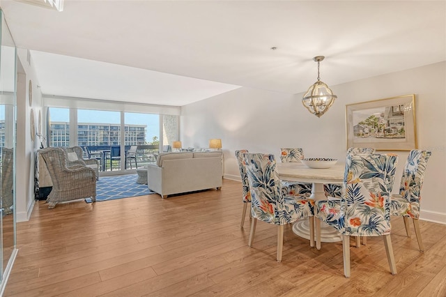 1115 Gulf Of Mexico Dr Unit 304, Longboat Key, FL 34228 - dining area with a chandelier, light wood-type flooring, and baseboards