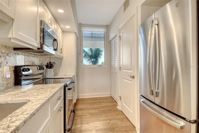 1115 Gulf Of Mexico Dr Unit 304, Longboat Key, FL 34228 - kitchen with stainless steel appliances, baseboards, light wood-type flooring, decorative backsplash, and white cabinets