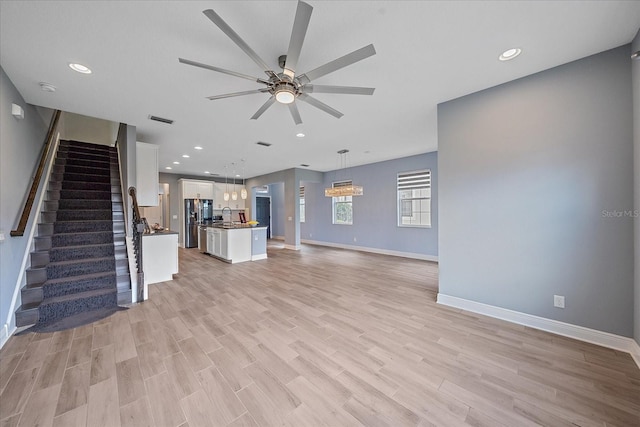 5191 78th St Cir E, Bradenton, FL 34203 - unfurnished living room with ceiling fan, light wood finished floors, baseboards, a sink, and stairway