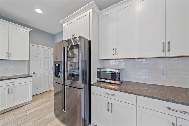 5191 78th St Cir E, Bradenton, FL 34203 - kitchen featuring stainless steel appliances, white cabinetry, dark stone countertops, backsplash, and light wood-type flooring