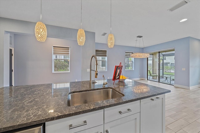 5191 78th St Cir E, Bradenton, FL 34203 - kitchen featuring a sink, white cabinetry, pendant lighting, baseboards, and dark stone counters