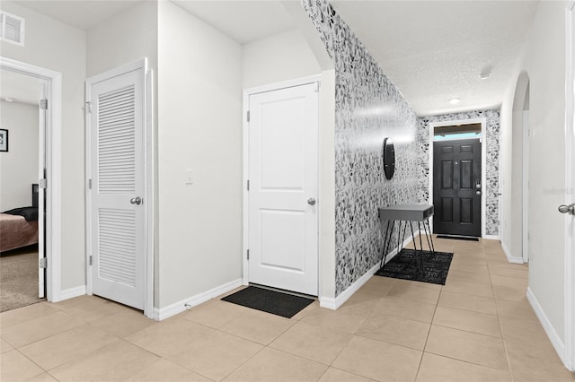 5659 Woodland Sage Dr, Sarasota, FL 34238 - tiled entryway with baseboards, arched walkways, and wallpapered walls