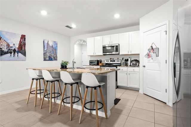 5659 Woodland Sage Dr, Sarasota, FL 34238 - kitchen with appliances with stainless steel finishes, a sink, light tile patterned flooring, a breakfast bar, and light stone countertops