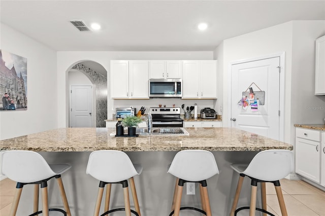 5659 Woodland Sage Dr, Sarasota, FL 34238 - kitchen featuring stainless steel appliances, a sink, light tile patterned flooring, white cabinets, and light stone countertops