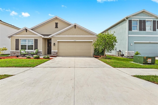 5659 Woodland Sage Dr, Sarasota, FL 34238 - craftsman inspired home featuring stone siding, stucco siding, driveway, a front yard, and a garage