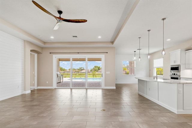 7508 Ripetta St, Sarasota, FL 34240 - unfurnished living room featuring a ceiling fan, a sink, baseboards, a raised ceiling, and recessed lighting