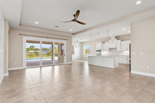 7508 Ripetta St, Sarasota, FL 34240 - unfurnished living room with ceiling fan, baseboards, recessed lighting, and a tray ceiling