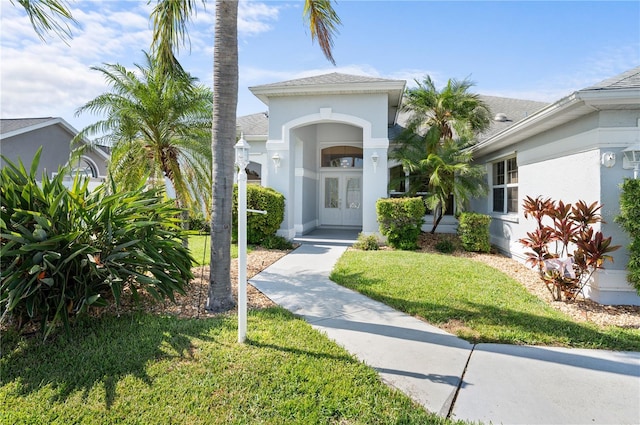 5110 19th Ave W, Bradenton, FL 34209 - view of front of house featuring french doors, stucco siding, a front lawn, and roof with shingles