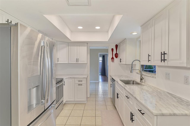 4155 Center Gate Blvd, Sarasota, FL 34233 - kitchen with appliances with stainless steel finishes, a sink, a tray ceiling, light tile patterned floors, and white cabinets