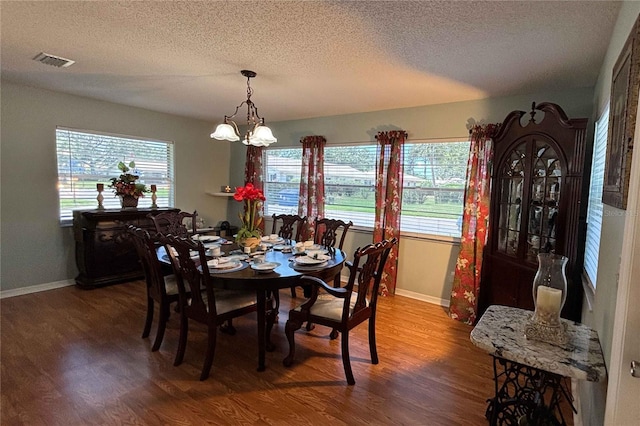 1111 Harefield Cir, Sun City Center, FL 33573 - dining area featuring a textured ceiling, wood finished floors, baseboards, and a chandelier