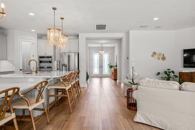 8932 Isabella Cir, Parrish, FL 34219 - kitchen featuring open floor plan, french doors, light countertops, appliances with stainless steel finishes, and backsplash