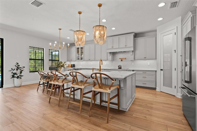 8932 Isabella Cir, Parrish, FL 34219 - kitchen with high end fridge, a chandelier, a sink, backsplash, and gray cabinetry