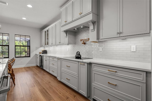 8932 Isabella Cir, Parrish, FL 34219 - kitchen with gray cabinets, black electric stovetop, baseboards, beverage cooler, and recessed lighting