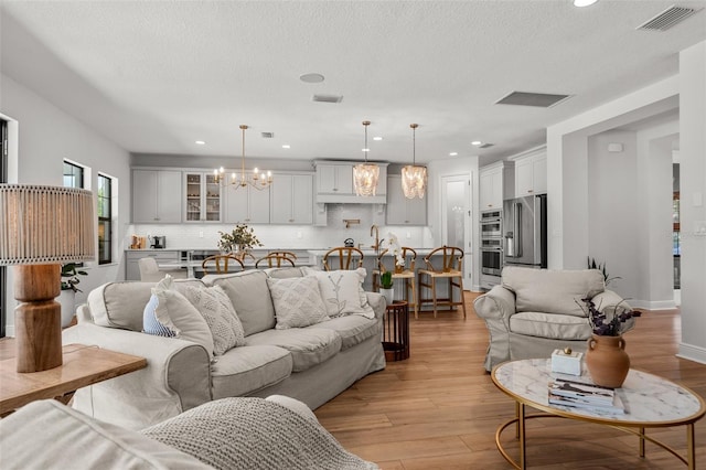 8932 Isabella Cir, Parrish, FL 34219 - living room featuring a chandelier, light wood-style floors, a textured ceiling, and recessed lighting