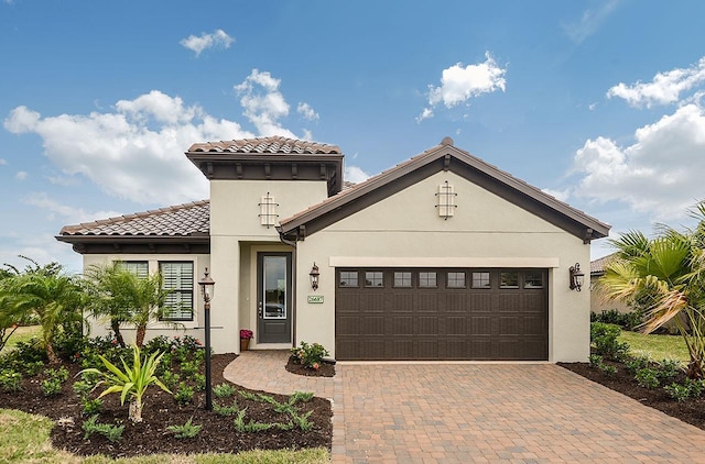26687 Raphis Royale Blvd, Englewood, FL 34223 - mediterranean / spanish house featuring decorative driveway, an attached garage, stucco siding, and a tiled roof