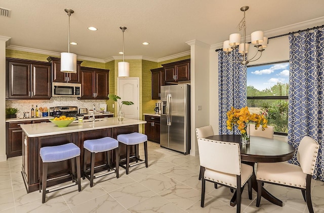 26687 Raphis Royale Blvd, Englewood, FL 34223 - kitchen with appliances with stainless steel finishes, light marble finish floors, a chandelier, light countertops, and a breakfast bar area