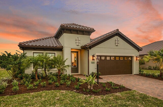 26687 Raphis Royale Blvd, Englewood, FL 34223 - mediterranean / spanish-style house with a garage, decorative driveway, stucco siding, and a tile roof