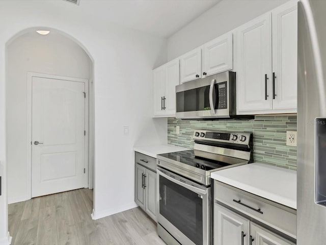 262 Cape Harbour Loop Unit 101, Bradenton, FL 34212 - kitchen with stainless steel appliances, backsplash, arched walkways, light countertops, and light wood finished floors
