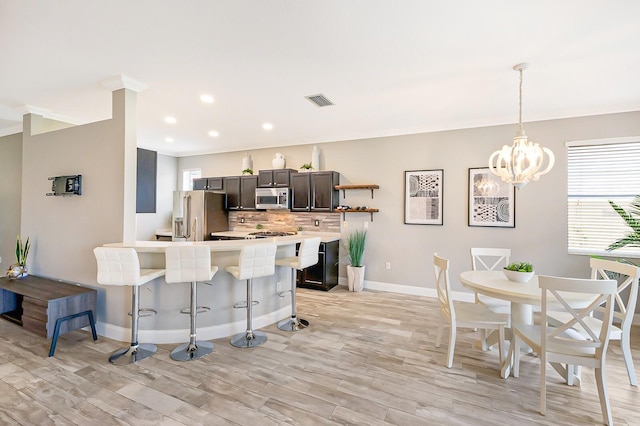 8640 Stone Harbour Loop, Bradenton, FL 34212 - kitchen featuring appliances with stainless steel finishes, a kitchen bar, backsplash, light countertops, and a peninsula