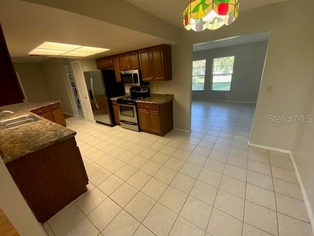 6923 13th Ave E, Bradenton, FL 34208 - kitchen featuring stainless steel appliances, a sink, light tile patterned floors, baseboards, and a peninsula