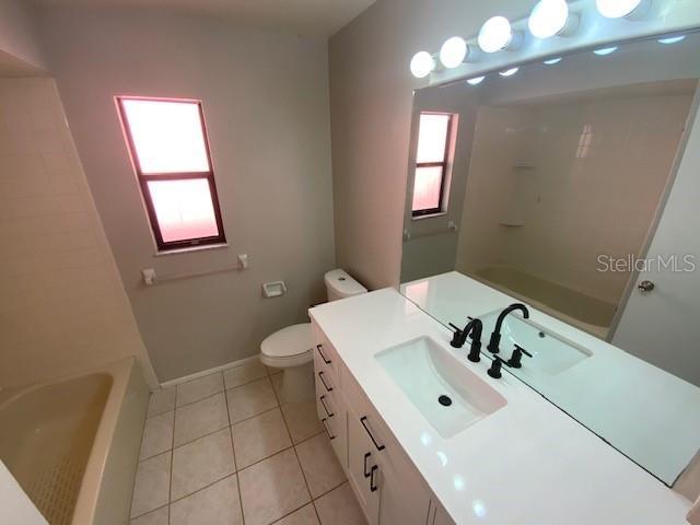 6923 13th Ave E, Bradenton, FL 34208 - bathroom with plenty of natural light, vanity, toilet, and tile patterned flooring