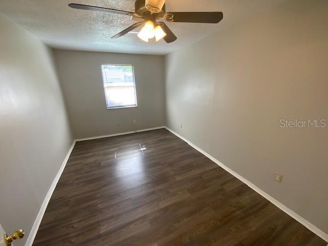 6923 13th Ave E, Bradenton, FL 34208 - unfurnished room with dark wood-style flooring, a ceiling fan, baseboards, and a textured ceiling