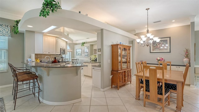 4612 4th Ave E, Bradenton, FL 34208 - kitchen with a peninsula, a breakfast bar, a chandelier, stainless steel microwave, and dark stone countertops