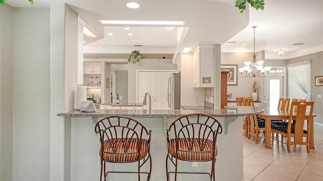 4612 4th Ave E, Bradenton, FL 34208 - kitchen featuring crown molding, freestanding refrigerator, light tile patterned floors, light stone counters, and white cabinets