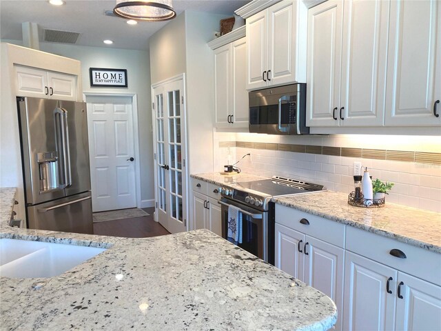 2149 Muskogee Trl, Nokomis, FL 34275 - kitchen featuring stainless steel appliances, white cabinetry, tasteful backsplash, light stone counters, and dark wood finished floors